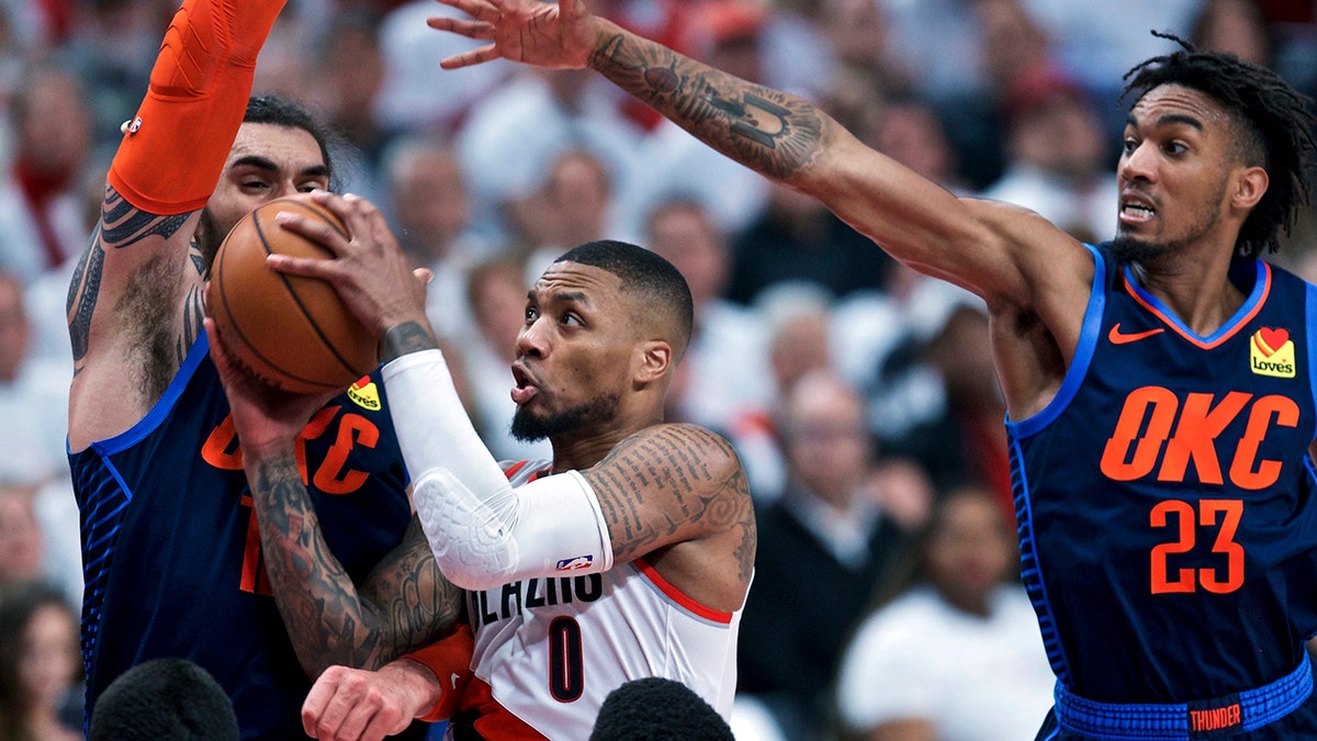 Portland Trail Blazers guard Damian Lillard, center, shoots between Oklahoma City Thunder center Steven Adams, left, and guard Terrance Ferguson, right, during the second half of Game 5 of an NBA basketball first-round playoff series, Tuesday, April 23, 2019, in Portland, Ore. The Trail Blazers won 118-115. (AP Photo/Craig Mitchelldyer)