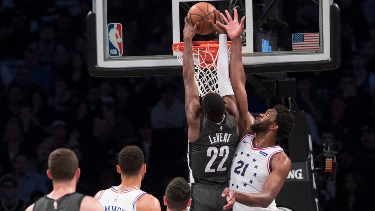 Brooklyn Nets guard Caris LeVert (22) dunks past Philadelphia 76ers center Joel Embiid (21) during the first half of Game 4 of a first-round NBA basketball playoff series, Saturday, April 20, 2019, in New York. (AP Photo/Mary Altaffer)