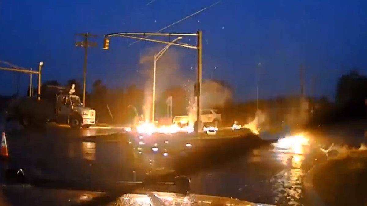 Flames can be seen after a powerline fell to the wet ground and exploded into a fireball as a utility worker was nearby in New Jersey on Monday.