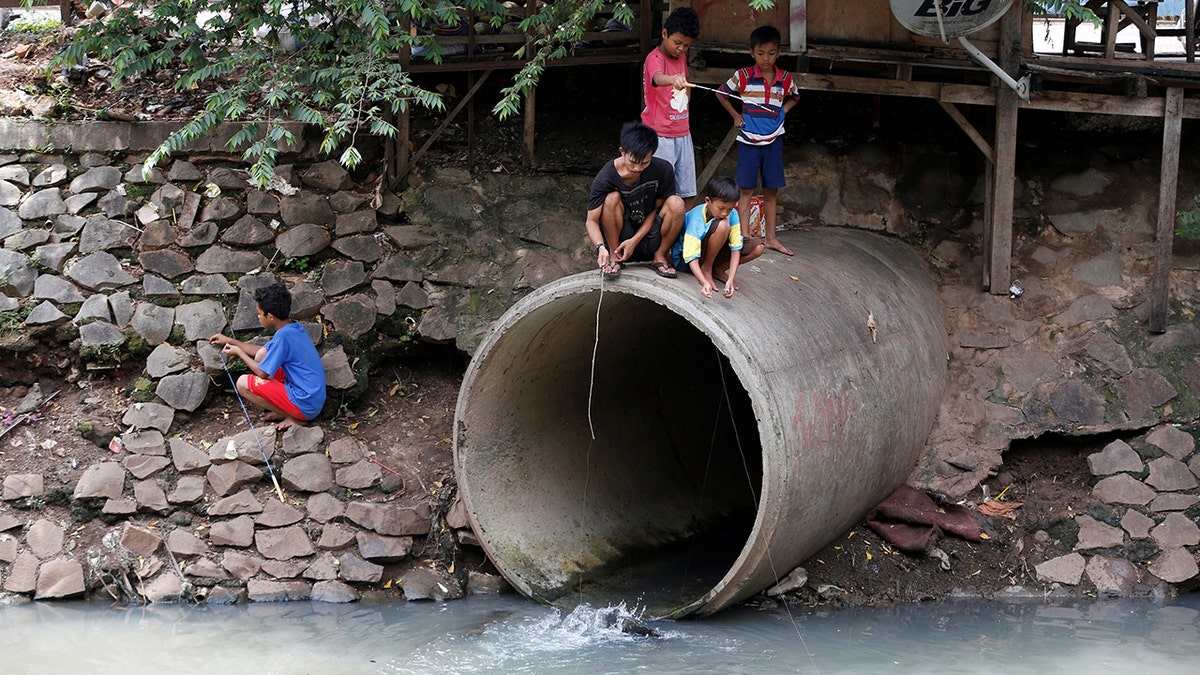 Children fish at a drainage pipe on a polluted canal in Jakarta, Indonesia November 18, 2016. Picture taken November 18, 2016.REUTERS/Darren Whiteside - S1BEUNQMJAAA