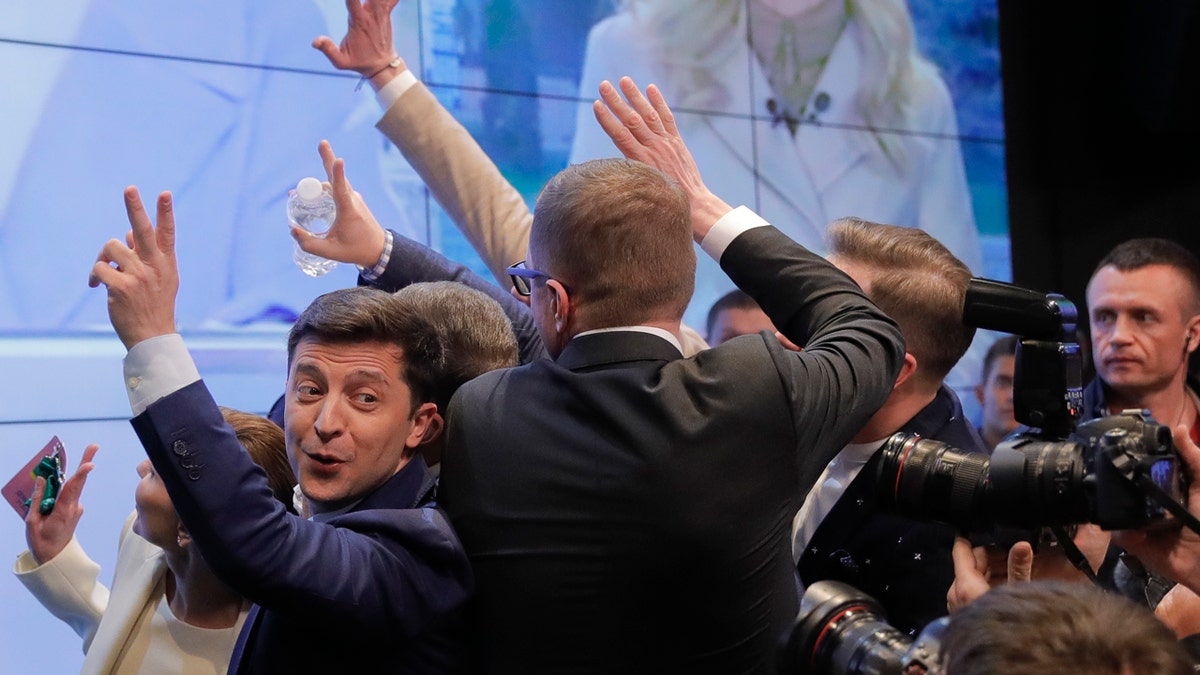 In this Sunday, April 21, 2019, photo, Ukrainian comedian and presidential candidate Volodymyr Zelenskiy, left, makes the victory sign after seeing the exit polls for the second round of presidential elections in Kiev, Ukraine.