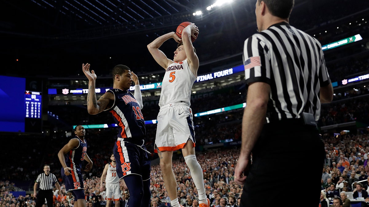 Virginia's Kyle Guy (5) takes a shot as Auburn's Samir Doughty (10) was called foul during the second half in the semifinals of the Final Four NCAA college basketball tournament, Saturday, April 6, 2019, in Minneapolis. (Associated Press)