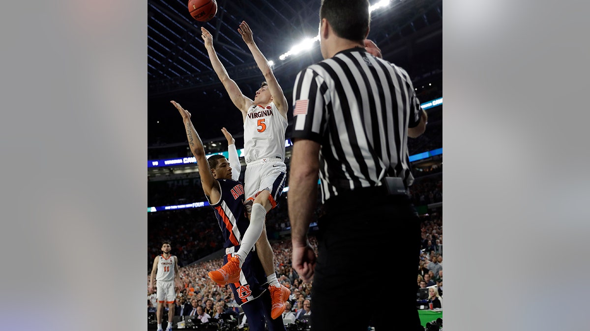 Virginia's Kyle Guy (5) takes a shot as Auburn's Samir Doughty (10) was called for a foul with 0.6 seconds left in the semi-final. (AP Photo/David J. Phillip)