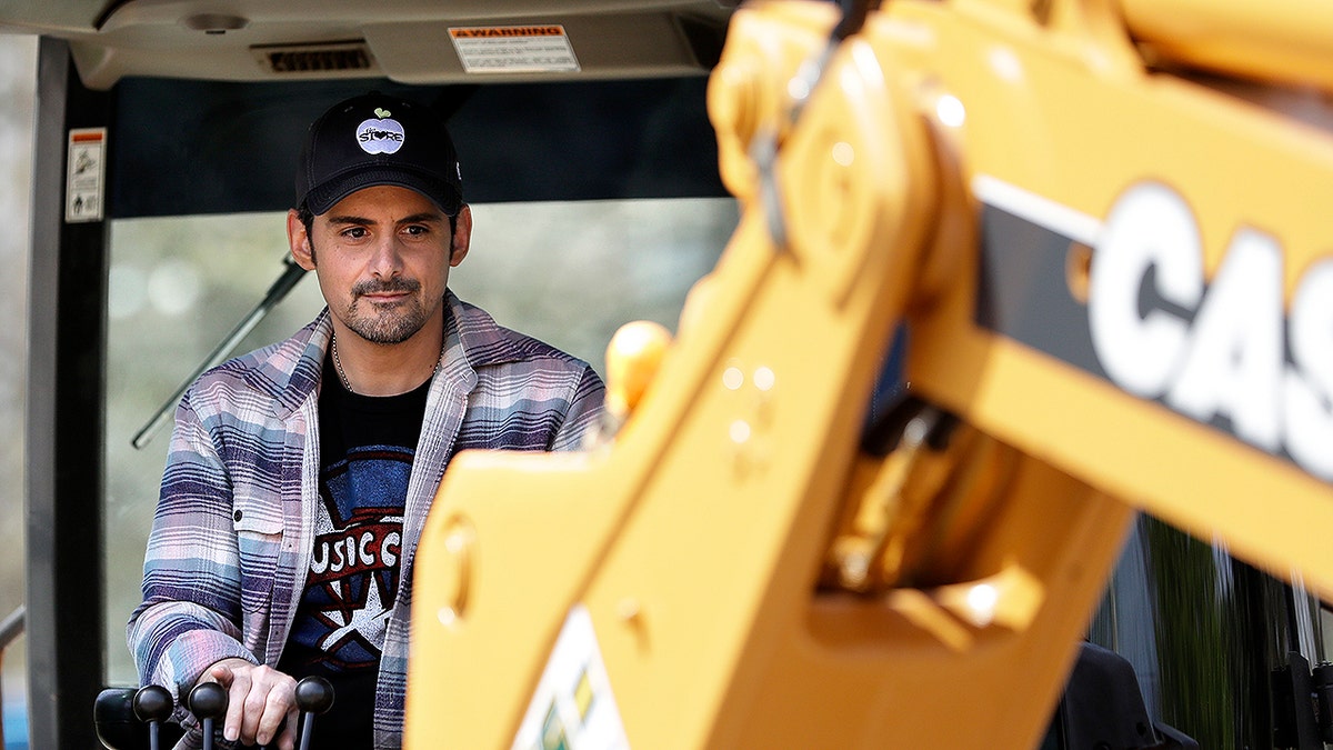 Country music star Brad Paisley operates a backhoe as he breaks ground for The Store, a free grocery store for people in need, Wednesday, April 3, 2019, in Nashville, Tenn. (AP Photo/Mark Humphrey)