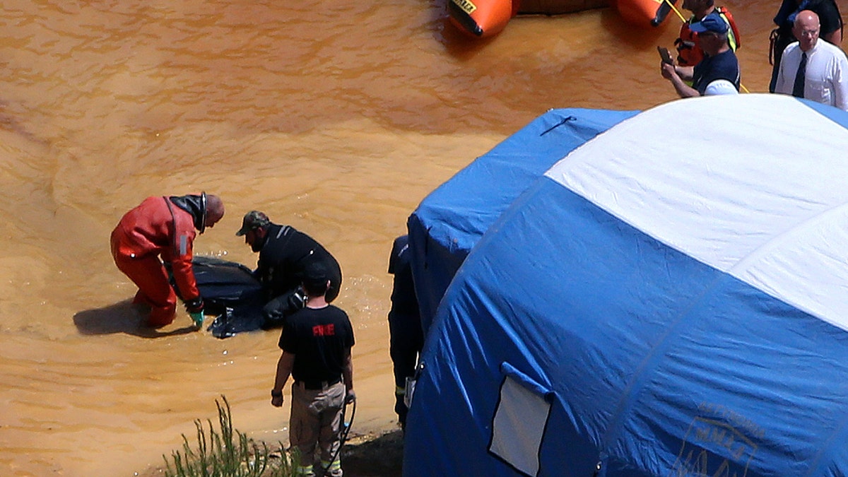 A travel suitcase containing the decomposing remains of an adult woman and a concrete block was retrieved from the bottom of a man-made lake, officials said Sunday.