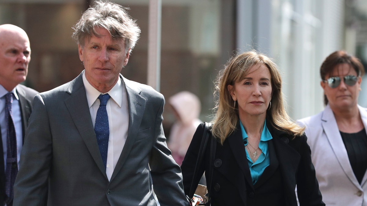 Actress Felicity Huffman arrives holding hands with her brother Moore Huffman Jr., left, at federal court in Boston on Wednesday, April 3, 2019, to face charges in a nationwide college admissions bribery scandal. (AP Photo/Charles Krupa)