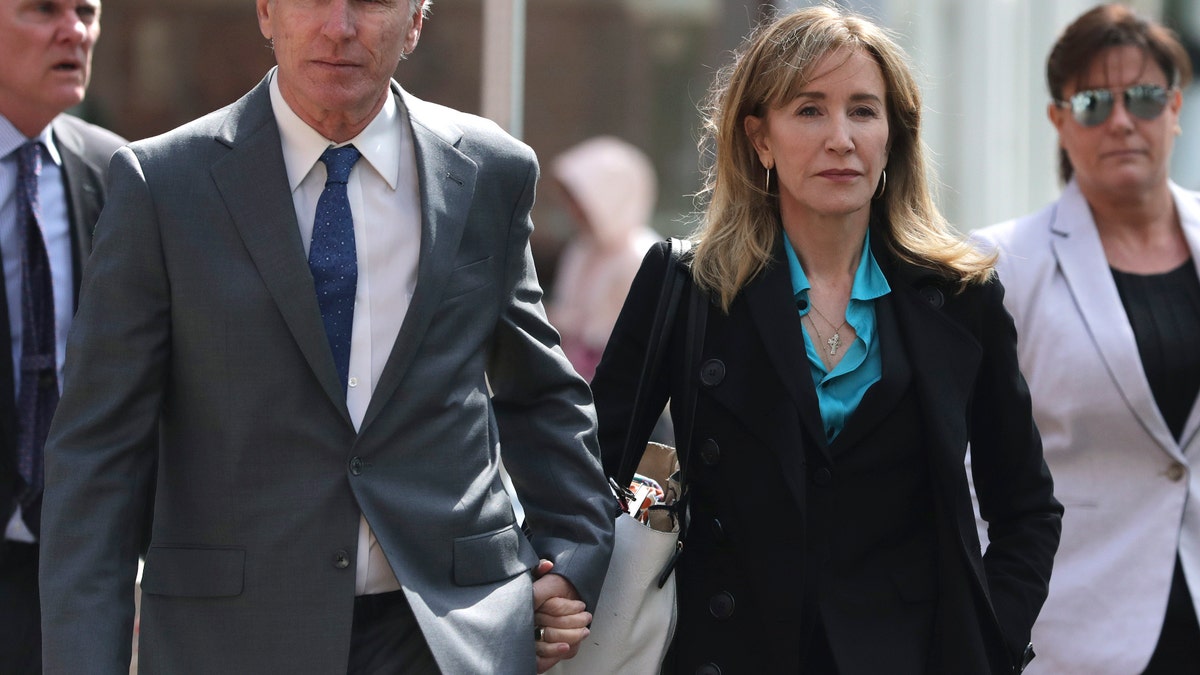 Actress Felicity Huffman arrives holding hands with her brother Moore Huffman Jr., left, at federal court in Boston on Wednesday, April 3, 2019, to face charges in a nationwide college admissions bribery scandal. (AP Photo/Charles Krupa)