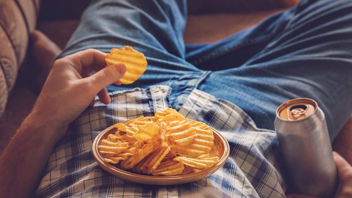 man on couch with chips