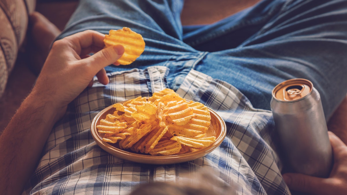 man on couch with chips