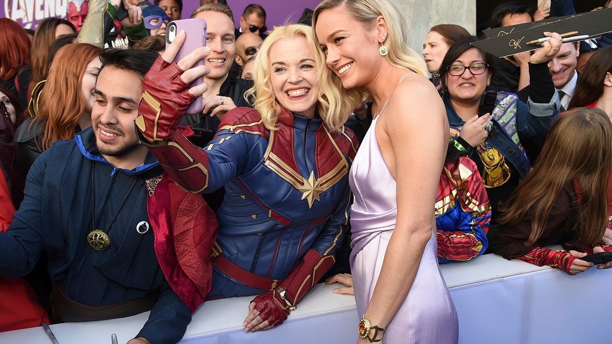 Brie Larson takes a selfie with a fan as she arrives at the premiere of 