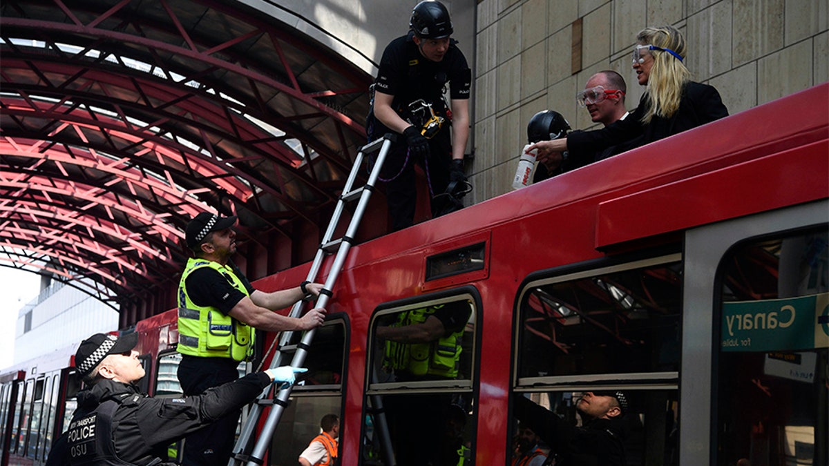 Police remove climate activists who glued themselves on top of a Dockland Light Railway train at Canary Wharf station in east London as part of the ongoing climate change protests.