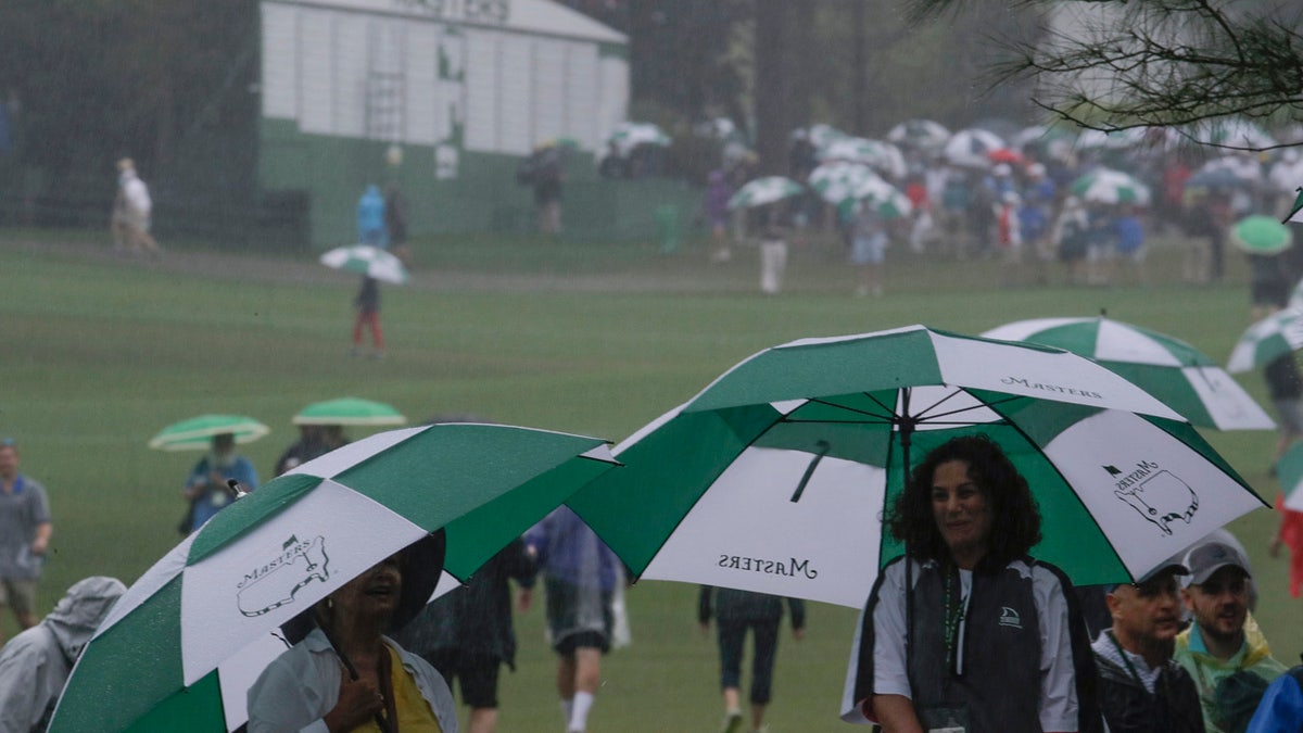 Fans use umbrellas near the ninth hole during the second round for the Masters golf tournament Friday, April 12, 2019, in Augusta, Ga. (AP Photo/Charlie Riedel)