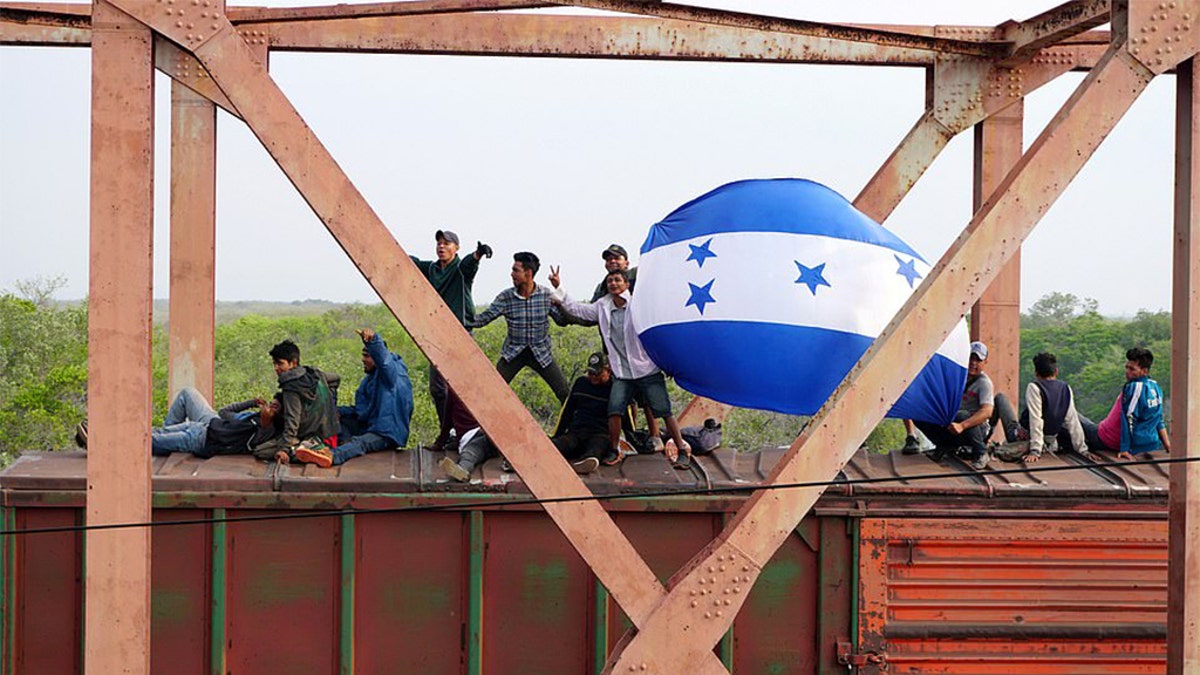 Central American migrants hold Honduras' national flag, while moving in a caravan through Juchitan, Oaxaca atop a train known as "The Beast" towards the United States, in Mexico April 26, 2019.