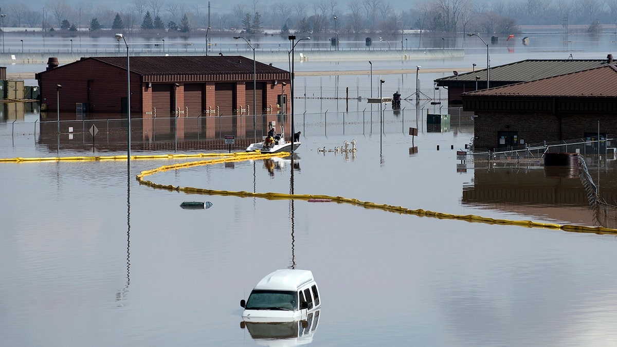 Environmental restoration employees deploy a containment boom from a boat on Offutt Air Force Base in Neb., as a precautionary measure for possible fuel leaks in the flooded area.