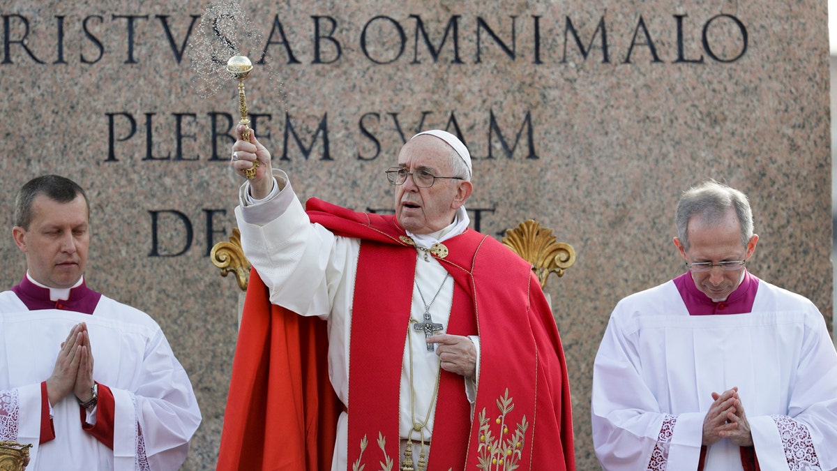 Pope Francis asperses holy water as he celebrates Palm Sunday Mass in St. Peter's Square at the Vatican, Sunday, April 14, 2019.