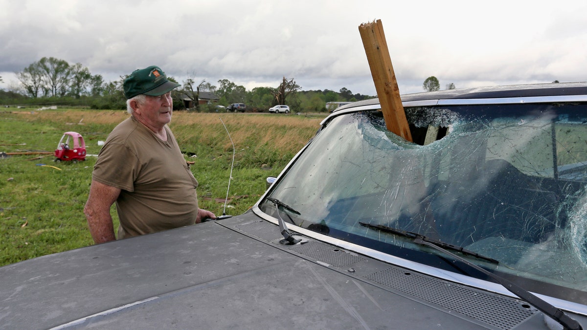 A man looks at a piece of wood that was blown through the windshield of his daughters truck in Hamilton, Miss., after a storm moved through the area Sunday, April 14, 2019.