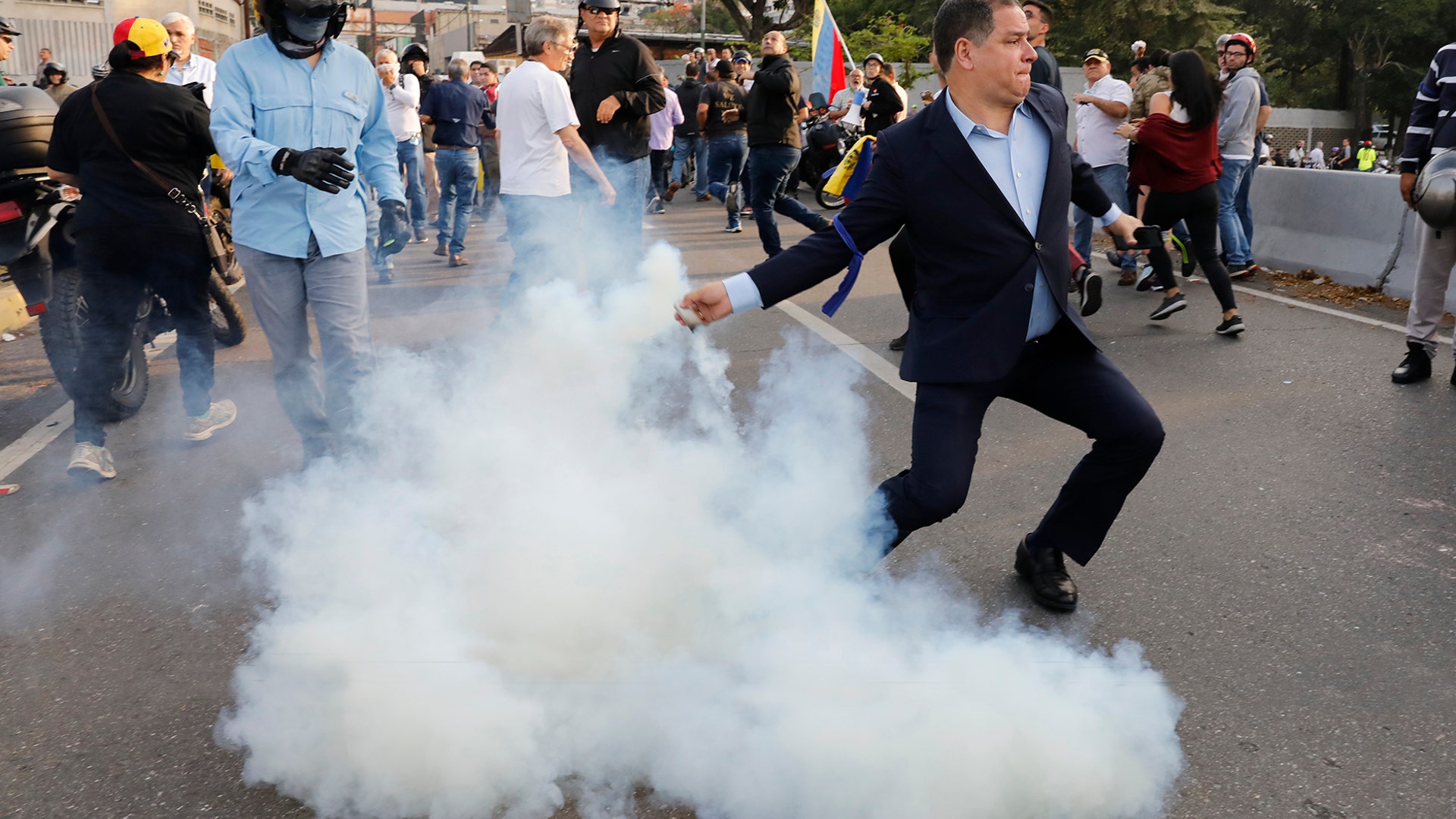 An opponent to Venezuela's President Nicolas Maduro returns a tear gas canister in Caracas, Venezuela, April 30, 2019.