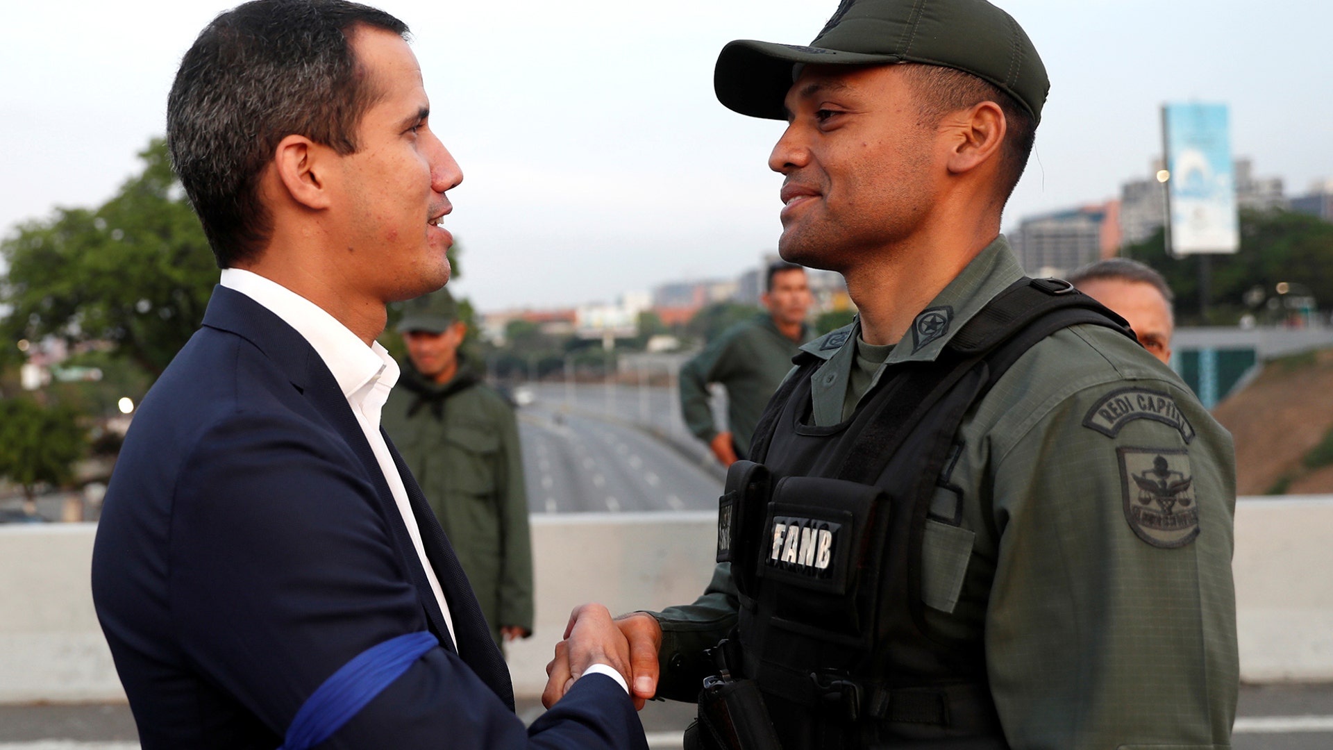 Venezuelan opposition leader Juan Guaido, who many nations have recognized as the country's rightful interim ruler, shakes hands with a military member near the Generalisimo Francisco de Miranda Airbase, in Caracas, April 30, 2019.