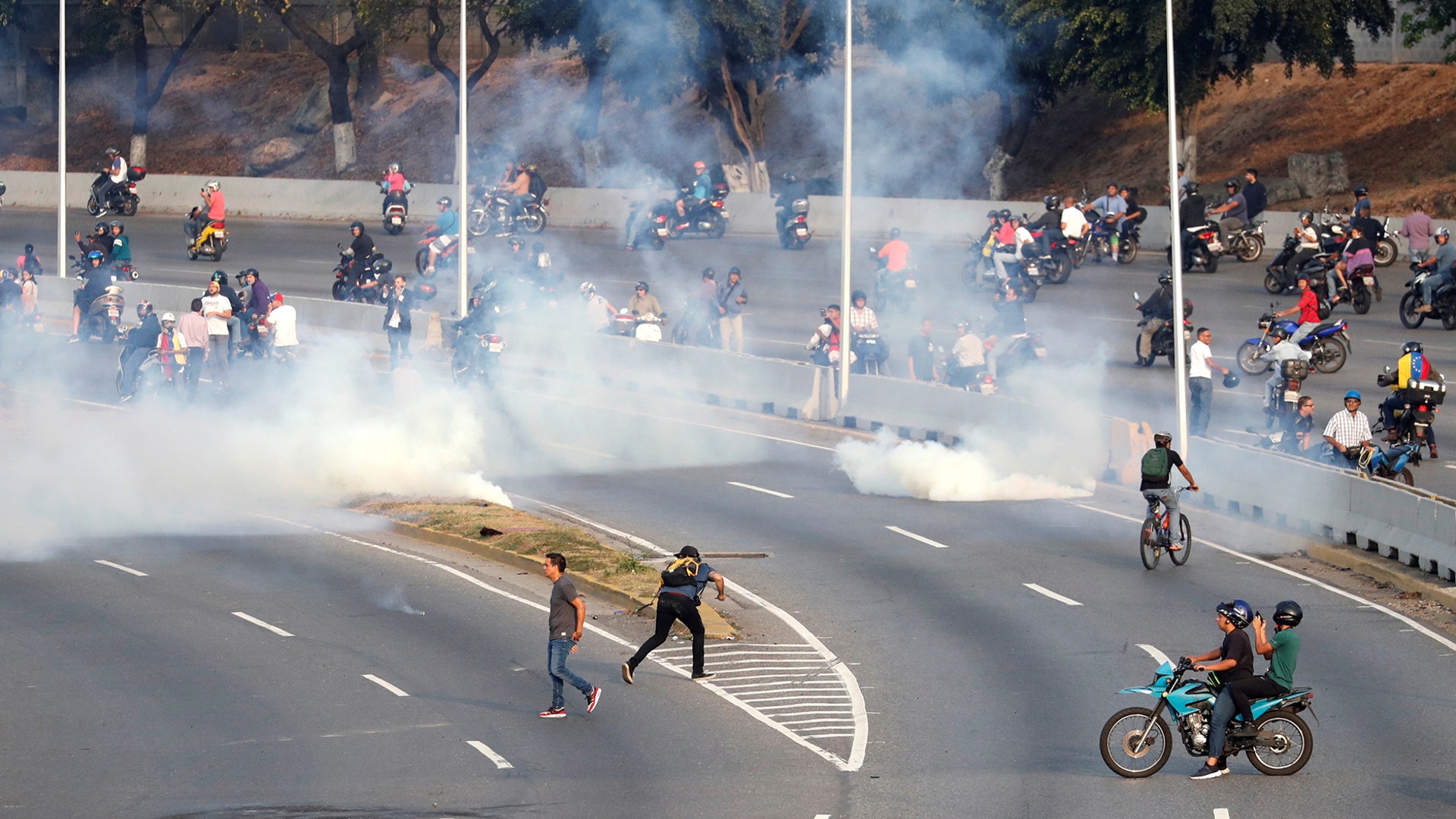People react to tear gas near the Generalisimo Francisco de Miranda Airbase in Caracas, April 30, 2019.