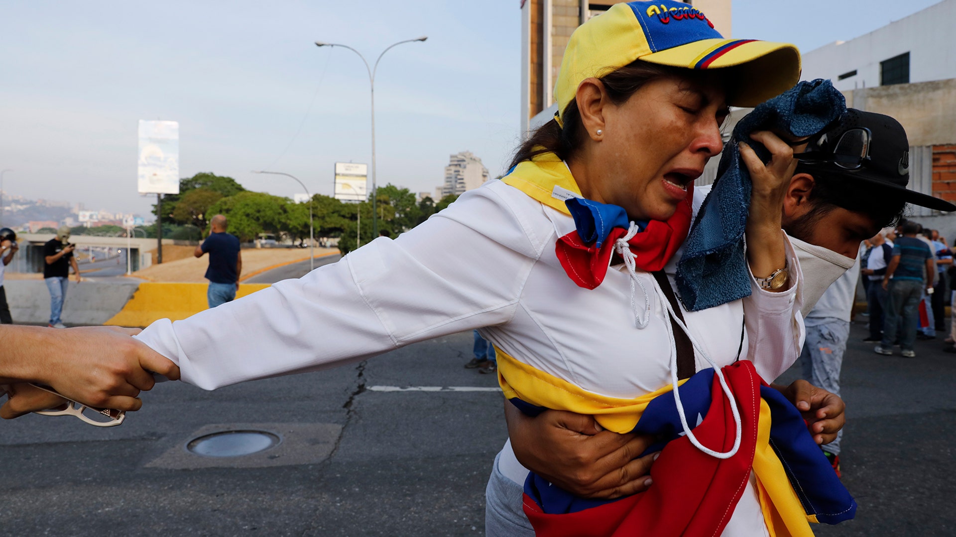 A woman suffocated by tear gas is helped by fellow opponents of President Nicolas Maduro outside La Carlota air base in Caracas, April 30, 2019.