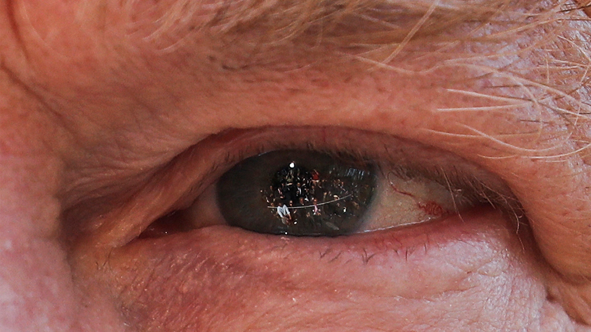 Members of the media are seen reflected in the eye of President Donald Trump as he answers questions on the South Lawn of the White House in Washington, April 10, 2019. 