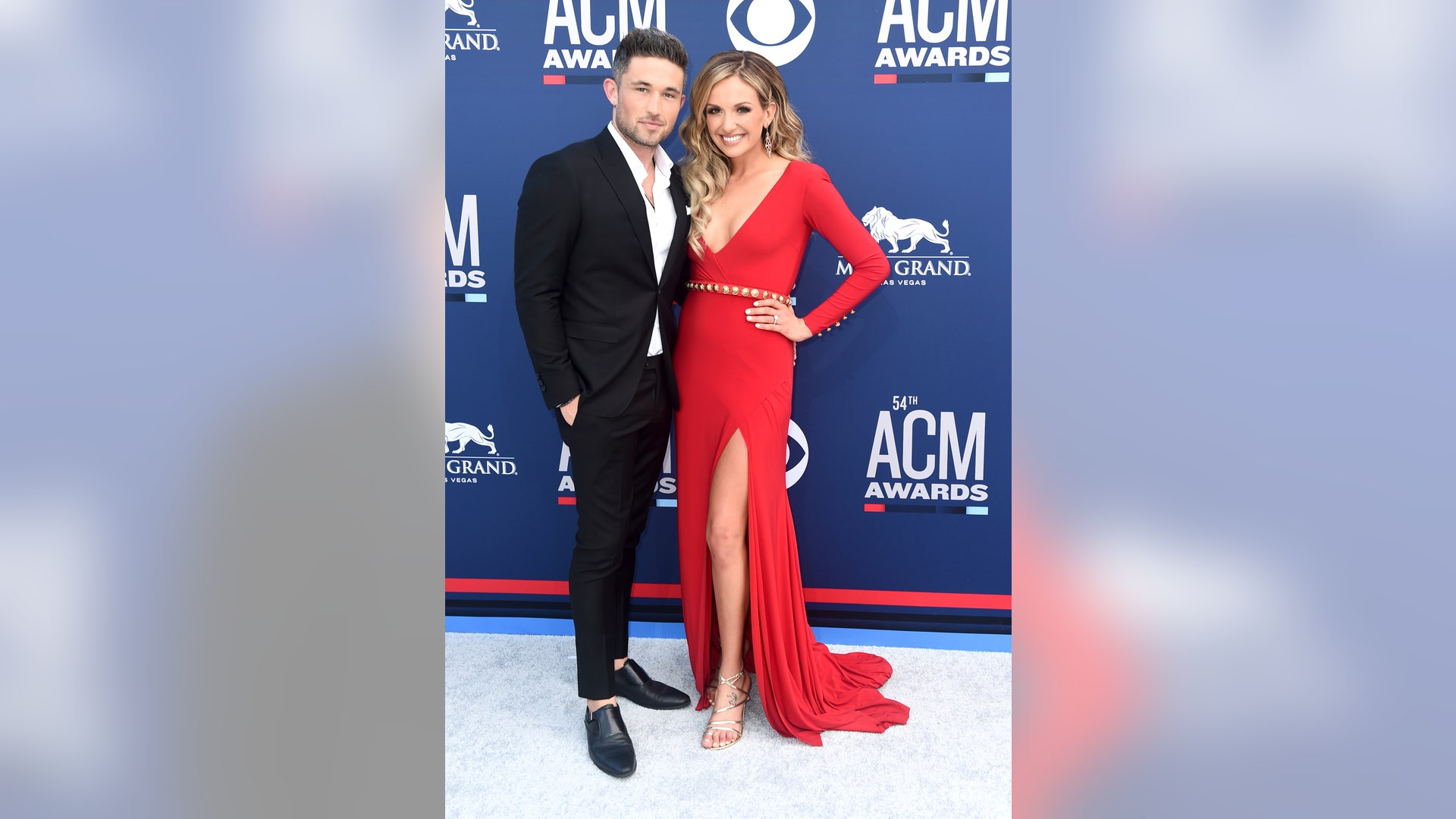 Michael Ray, in a black suit, and Carly Pearce, in a vibrant red gown with a plunging neckline, make it a date night at the 2019 ACM Awards.