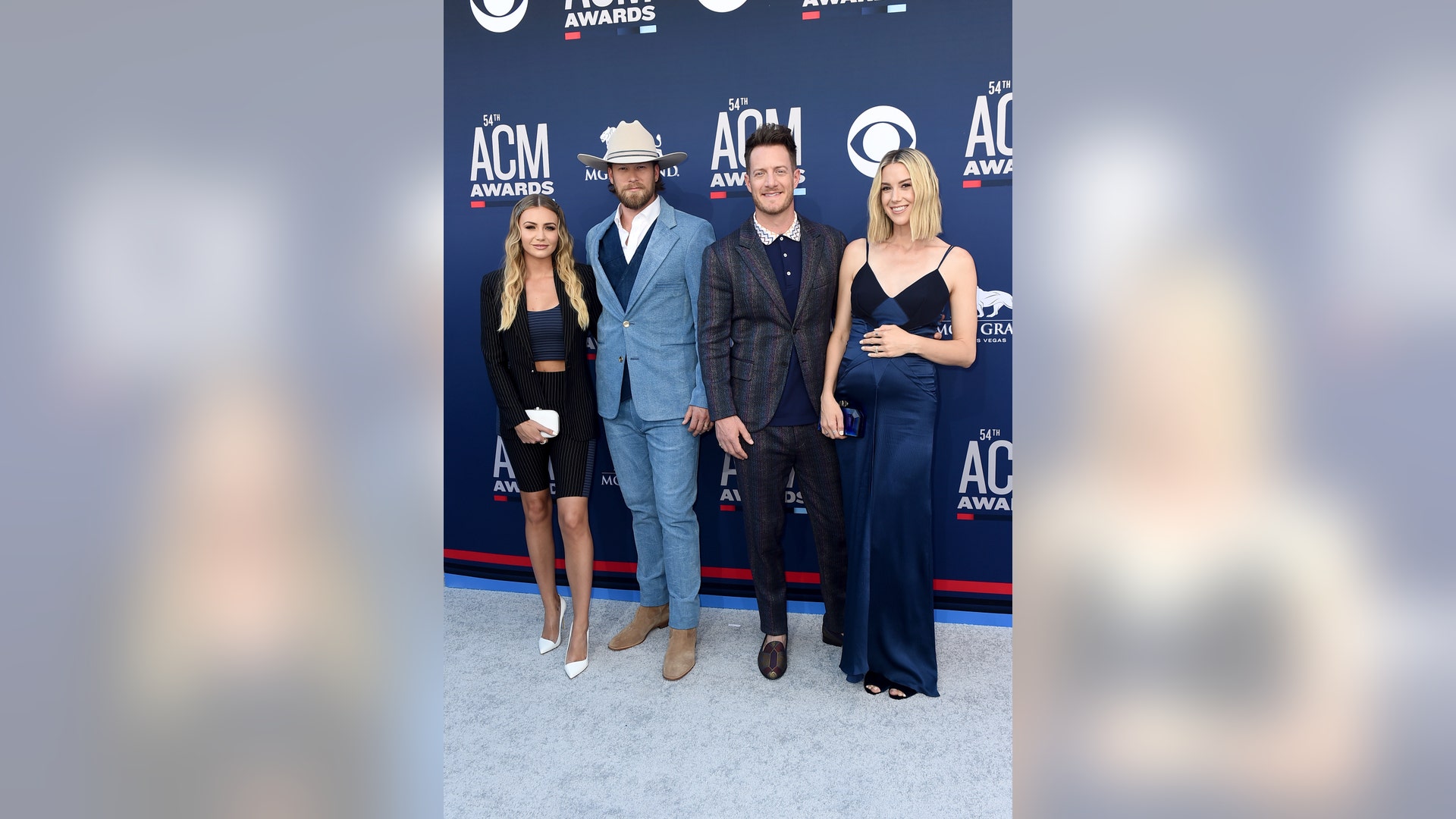Florida Georgia Line's Brian Kelley with wife Brittney Marie Cole and Tyler Hubbard with wife Hayley Stommell all color coordinate in navy blue outfits.