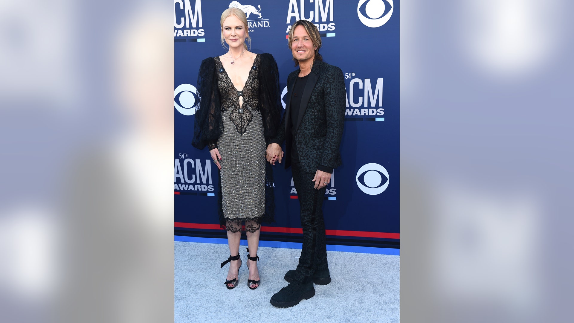 Nicole Kidman, in a shimmery number, and Keith Urban, in an animal print suit, hold hands at the 54th annual Academy of Country Music Awards.