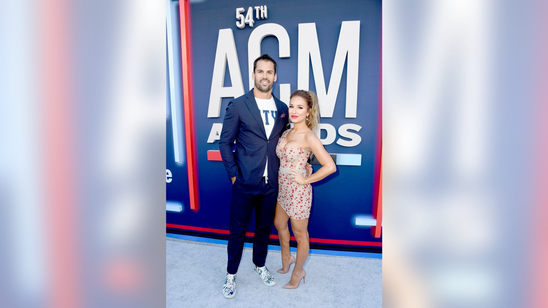 Eric Decker, in a blue suit, and Jessie James Decker, in a mini dress with heart detailing, keep close at the award show.