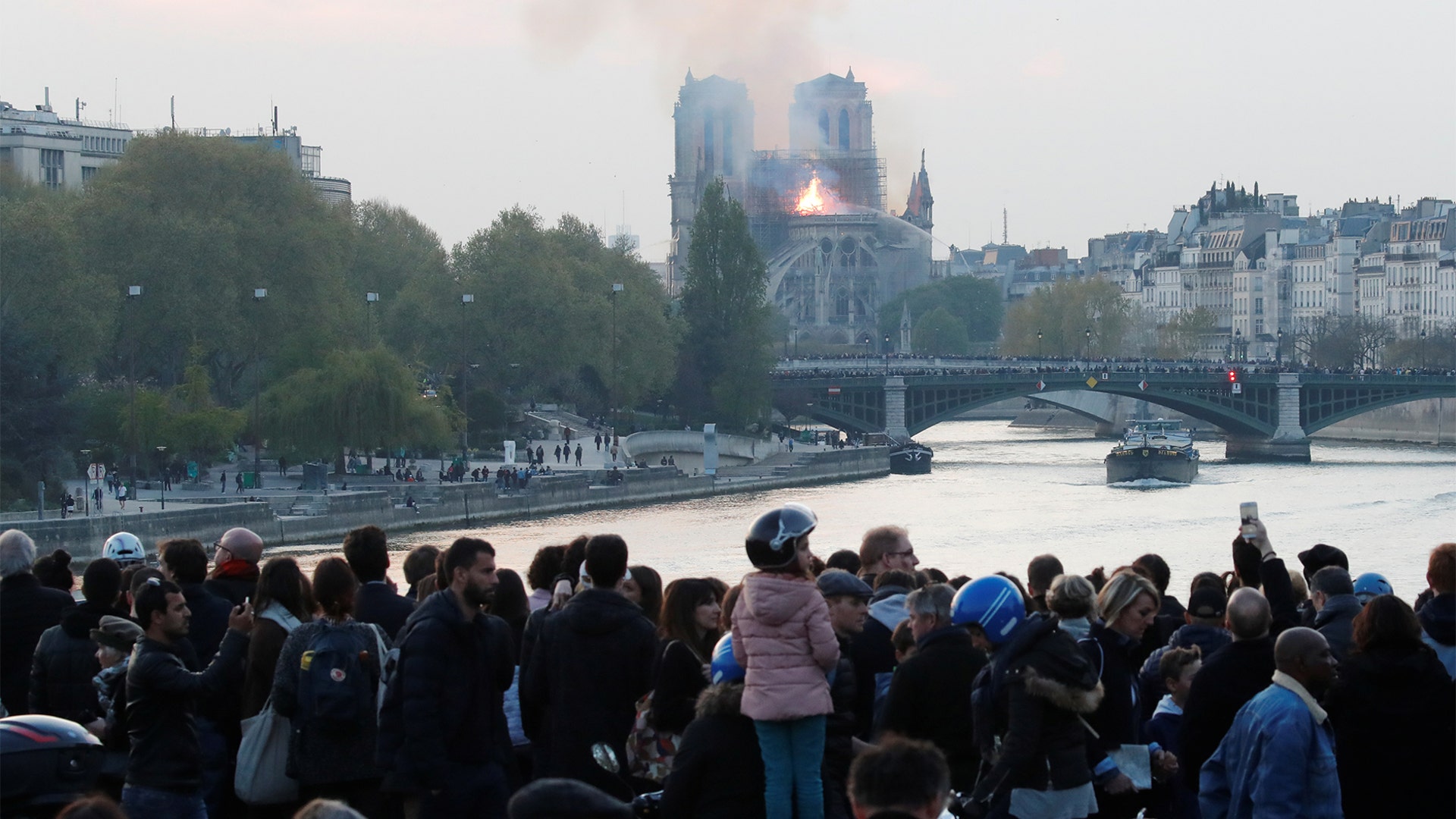 People watch as smoke billows from Notre Dame Cathedral.