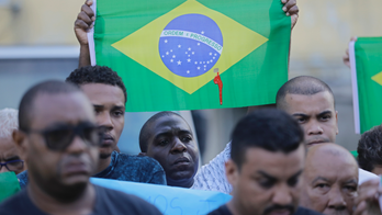 Red-stained Brazil flags at burial of man shot by military
