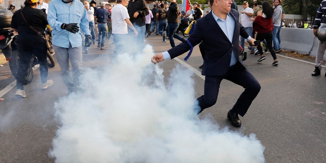 An opponent to Venezuela's President Nicolas Maduro returns a tear gas canister in Caracas, Venezuela, on Monday.