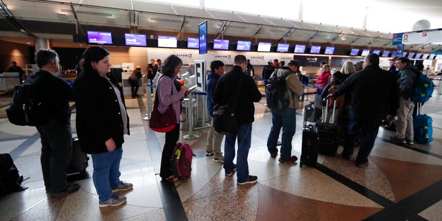 Passengers wait in a line to rebook their flights at the United Airlines counter in Denver International Airport Wednesday, April 10, 2019, in Denver.