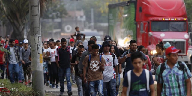 Migrants walk along a highway as a new caravan of several hundred people sets off from San Pedro Sula, Honduras, shortly after dawn on Wednesday, April 10, 2019, in hopes of reaching the distant United States.