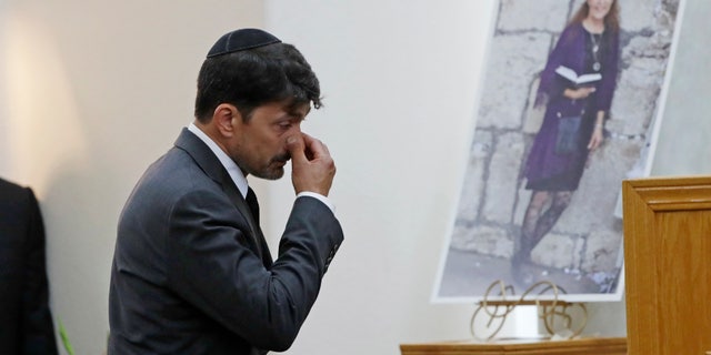 Oscar Stewart, left, walks past a photo of Lori Kaye, Monday, April 29, 2019, as he attends a memorial service for Kaye in Poway, Calif. Stewart was worshipping at the Chabad of Poway synagogue Saturday when a gunman opened fire, killing Kaye. (AP Photo/Gregory Bull)