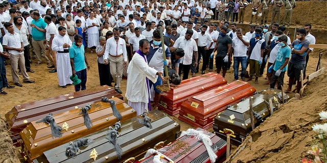 A priest conducts religious rituals during a mass burial for Easter Sunday bomb blast victims in Negombo, Sri Lanka, on Wednesday.