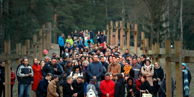 Local residents pray next to the line of wooden crosses marking the Soviet-era mass grave site in Kuropaty, in the Belarus capital Minsk, Thursday, April 4, 2019. Police in Belarus have arrested 15 demonstrators who were trying to prevent the removal of wooden crosses from a wooded area near the capital of Minsk where tens of thousands of people were executed under Soviet dictator Josef Stalin.