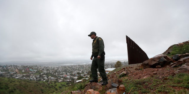 Border Patrol agent Vincent Pirro looks on near where a border wall ends that separates the cities of Tijuana, Mexico, left, and San Diego, in San Diego.