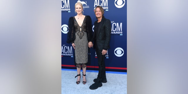Nicole Kidman, in a shimmery number, and Keith Urban, in an animal print suit, hold hands at the 54th annual Academy of Country Music Awards.