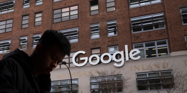 FILE - In this Dec. 17, 2018, file photo, a man using a mobile phone walks past Google offices in New York. Executives from Google and Facebook are facing Congress Tuesday, April 8, 2019, to answer questions about their role in the hate crimes and the rise of white nationalism in the U.S. (AP Photo/Mark Lennihan, File)