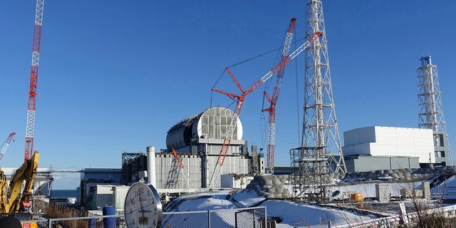 FILE - In this January 25, 2018 file photo, installation of a domed roof housing key equipment nears completion at the Fukushima Dai-ich nuclear power plant's Unit 3 reactor ahead of removal fuel from its storage pool in Okuma, Fukushima prefecture, northeast Japan.  Japan has partially lifted an evacuation order in one of the two hometowns of the Fukushima nuclear power plant destroyed by the tsunami for the first time since the 2011 disaster. The measure taken on Wednesday, April 10, 2019 allows people to return about 40% of Okuma.  The other hometown, Futaba, remains off-limits, as do several other nearby towns.  (AP Photo/Mari Yamaguchi, File)
