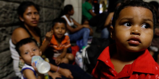 Migrants planning to join a new caravan of several hundred people setting out in hopes of reaching the distant United States, wait at the bus station in San Pedro Sula, Honduras, Tuesday, April 9, 2019. Parents who gathered at the bus station to leave with Wednesday morning's caravan say they can't support their families with what they can earn in Honduras and are seeking better opportunities. (AP Photo/Delmer Martinez)