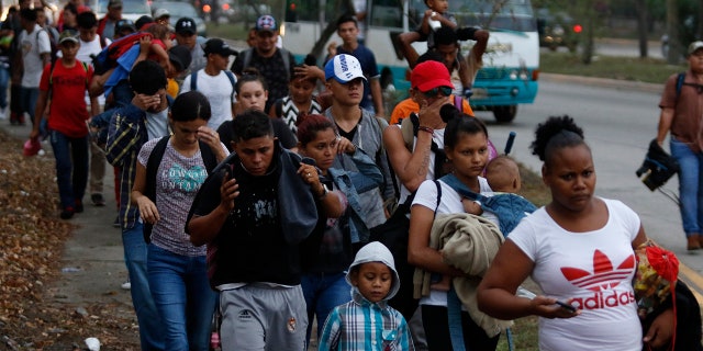 Migrants walk along a highway as a new caravan of several hundred people sets off in hopes of reaching the distant United States, in San Pedro Sula, Honduras, shortly after dawn Wednesday, April 10, 2019. Parents who gathered at the bus station with their children to join the caravan say they can't support their families with what they can earn in Honduras and are seeking better opportunities. (AP Photo/Delmer Martinez)