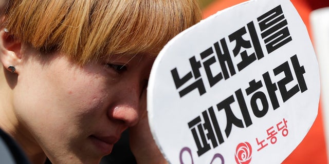 A woman wipes tears during a rally demanding the abolition of abortion law outside of the Constitutional Court in Seoul, South Korea on Thursday. (AP Photo/Lee Jin-man)