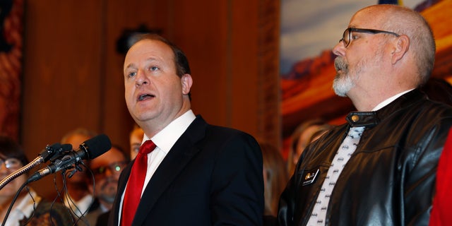 Colorado Governor Jared Polis, left, speaks as D-Aurora representative Tom Sullivan observes before Polis signs a bill to allow Colorado to become the 15th state of the union to adopt a 