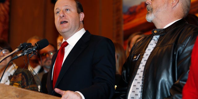 Colorado Governor Jared Polis, left, speaks as D-Aurora representative Tom Sullivan observes before Polis signs a bill to allow Colorado to become the 15th state of the union to adopt a 