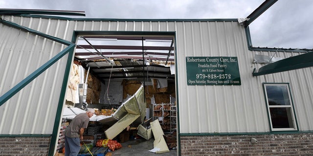 Jerry Redden takes a measurement outside Robertson County Care, Inc., after the food pantry was hit by a powerful storm, Saturday in Franklin, Texas. (Associated Press)