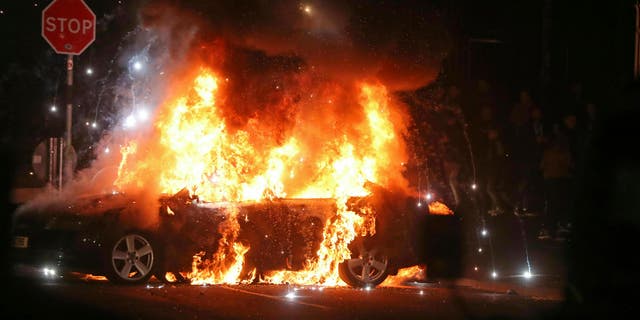 A journalist was shot to death during Northern Ireland rioting, Thursday, April 18, 2019. A car burns after petrol bombs were thrown at police in the Creggan area of Londonderry. 