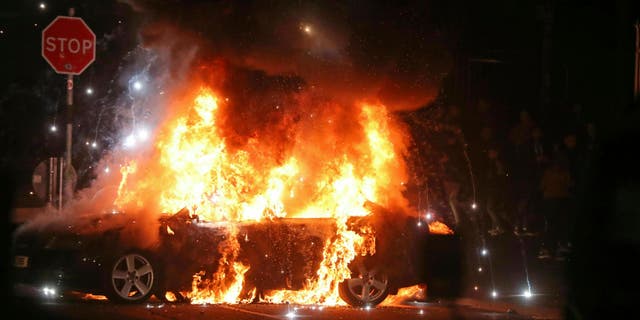 A journalist was shot to death during Northern Ireland rioting, Thursday, April 18, 2019. A car burns after petrol bombs were thrown at police in the Creggan area of Londonderry.