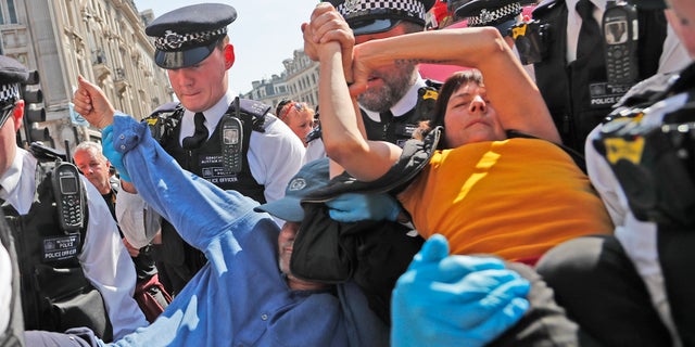 Police arrest a protestor couple who are glued together by their hands, at Oxford Circus in London, Friday, April 19, 2019. The group Extinction Rebellion is calling for a week of civil disobedience against what it says is the failure to tackle the causes of climate change